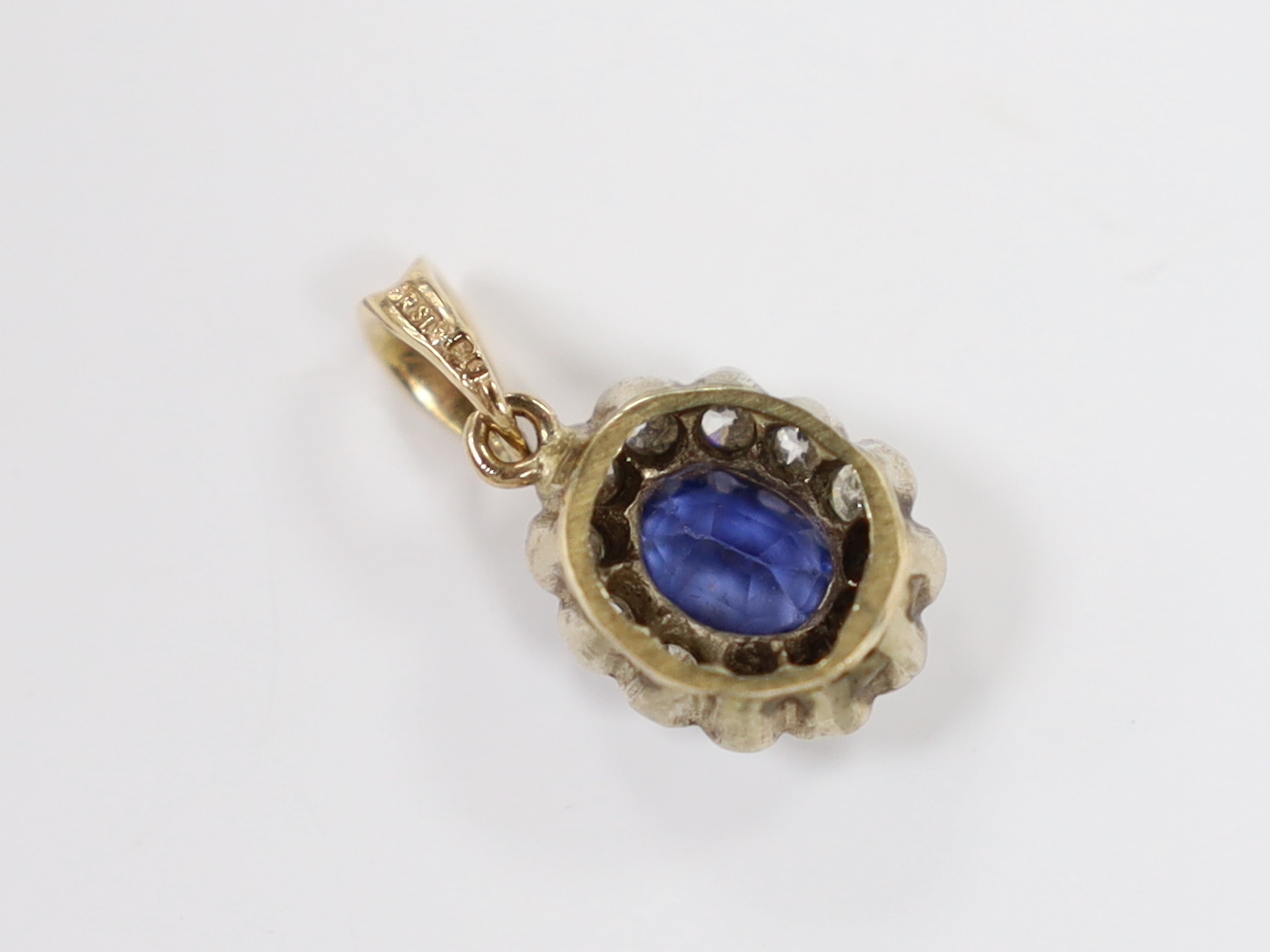 A yellow metal, synthetic sapphire and diamond set oval cluster pendant, overall 19mm, gross weight 1.5 grams.